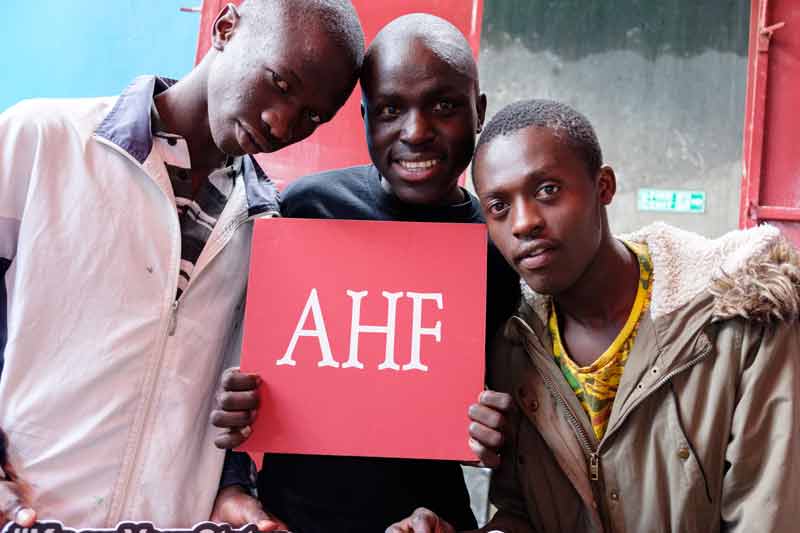 AHF Kenya 3 men client holding the AHF Sign
